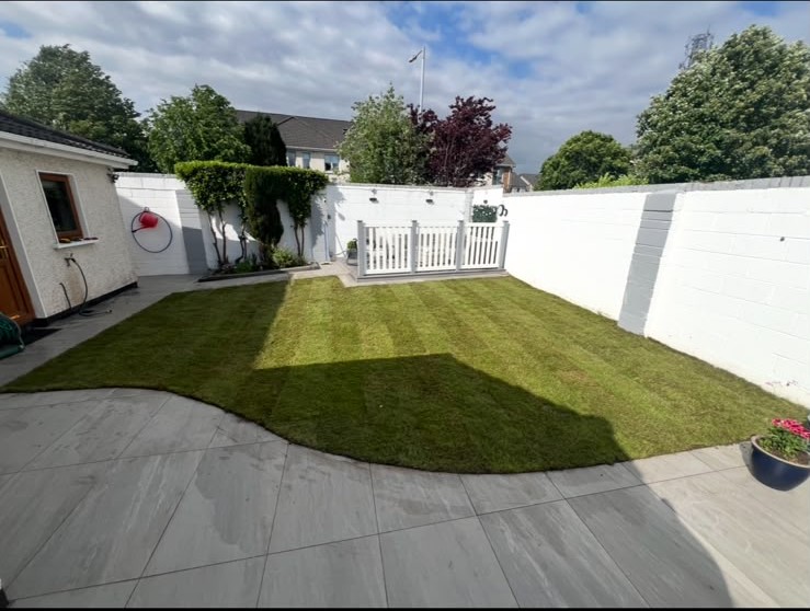 Freshly striped lawn beside a paved patio and white garden walls